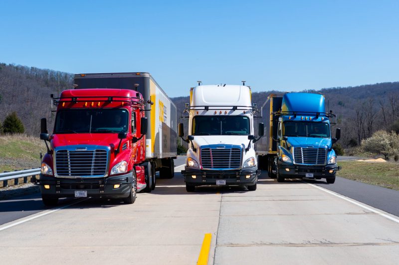 Three semi-trucks parked on a road.