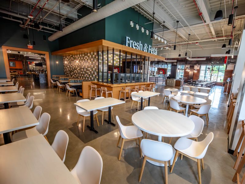 Dining tables and chairs are situated outside of Fresh & Feta inside of Perry Place.