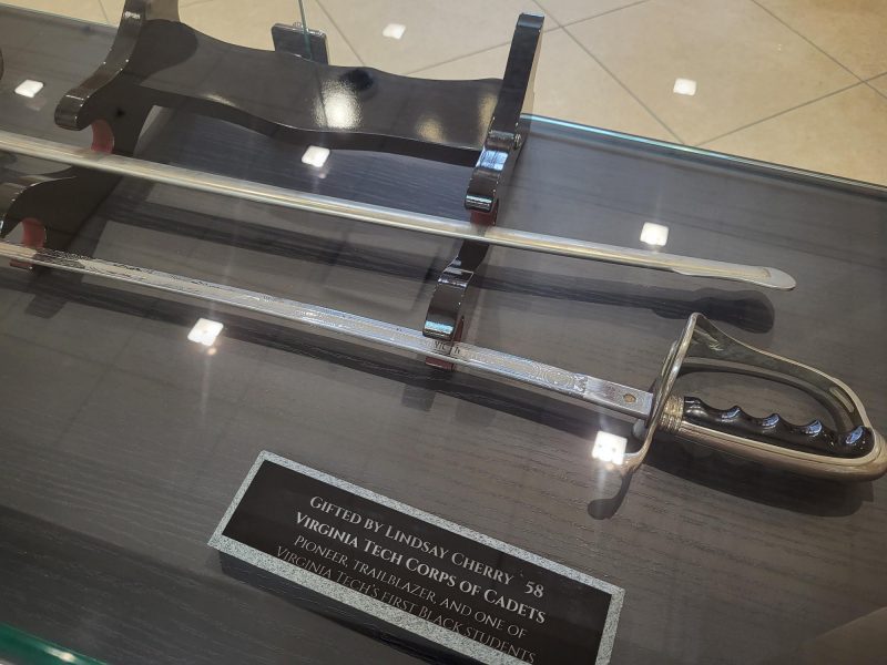 Ring and saber donated by Lindsay Cherry '58 A ring and saber on display in a glass case with a plaque indicating that they are a gift from Lindsay Cherry.