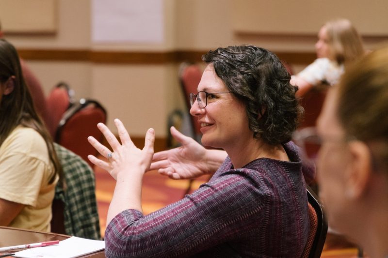 A female college instructor speaks while sitting in a meeting.