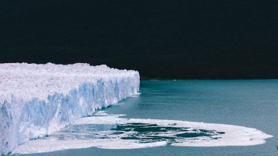 A massive glacier melting into the ocean on a dark night. 