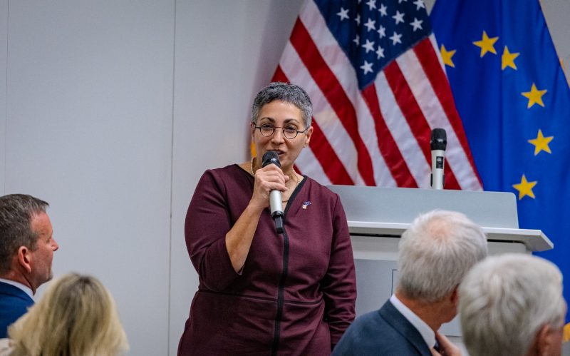 Female holds microphone and speaks during event.