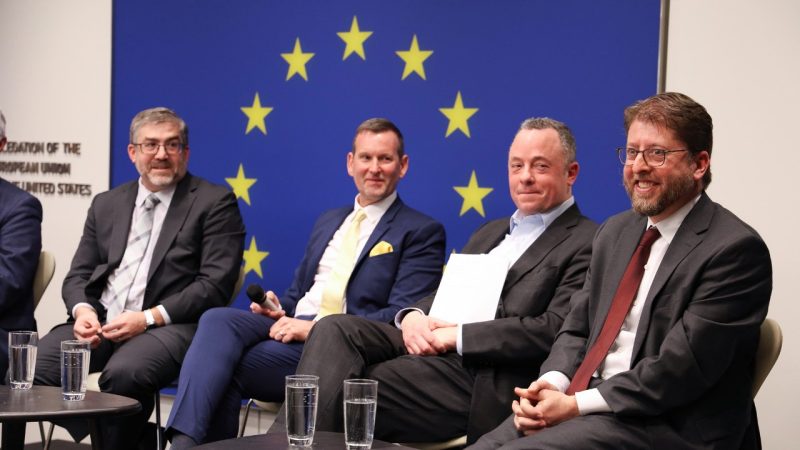 Four men sit in front of room during panel discussion.