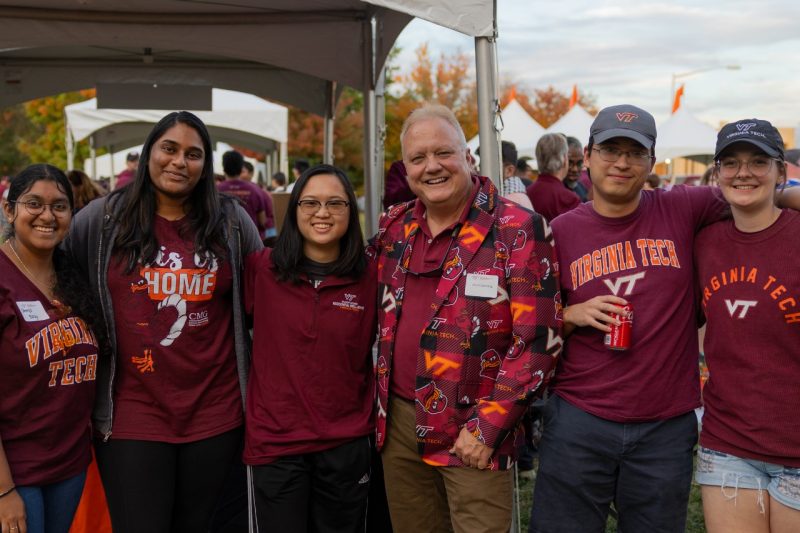 ECE Tailgate - Haley Rindfleisch A group of students and Dr. Scott Dunning are all wearing Virginia Tech gear. They have their arms around each other.
