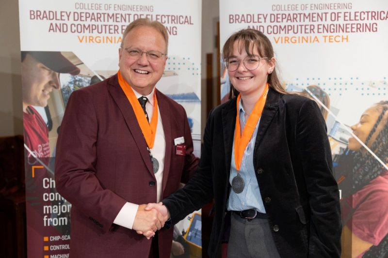 Haley Rindfleisch -- HLB Medal From left: Scott Dunning shakes heads with Haley Rindfleisch at the ECE Heta Lambda Beta induction ceremony on Nov. 20.