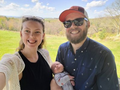 Carmen McBride with her husband and son. Carmen McBride (at left) holding a baby and standing next to a man.