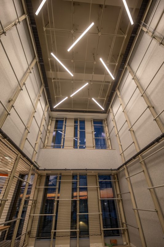 a tall room with netting on the sides and angular ceiling lights