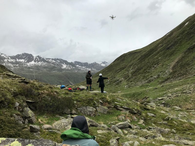 Scientist Philipp Baloh (foreground) watches David Schmale pilot a drone to collect a water sample with Regina Hanlon in Obergurgl, Tyrol, Austria. Photo courtesy of David Schmale.