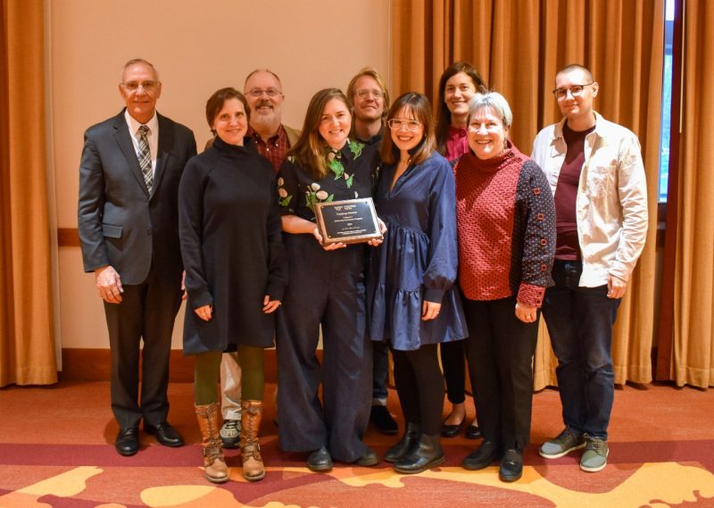 Eight representatives of the Language Sciences program pose with Executive Vice President and Provost Cyril Clark as they receive an award.