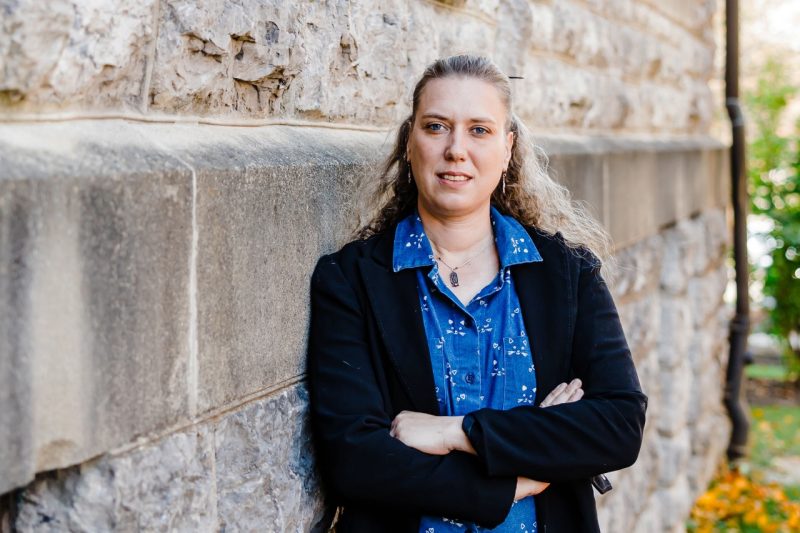 Marie Boër Woman stands with arms crossed next to building covered in Hokie Stone