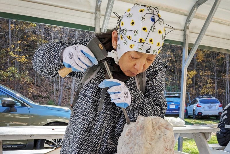 Person wearing EEG cap while carving a stone