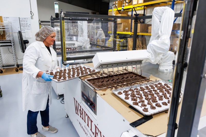 A factory worker handles trays of chocolates.