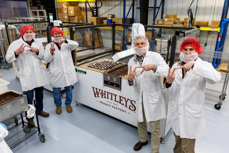 Four people in hair nets make the Virginia Tech hand sign.