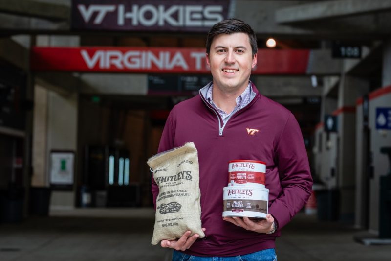 A man stands holding snack products.