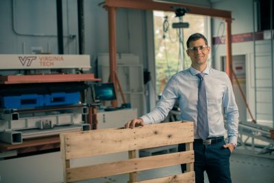 Man wearing tie and protective glasses in a warehouse.