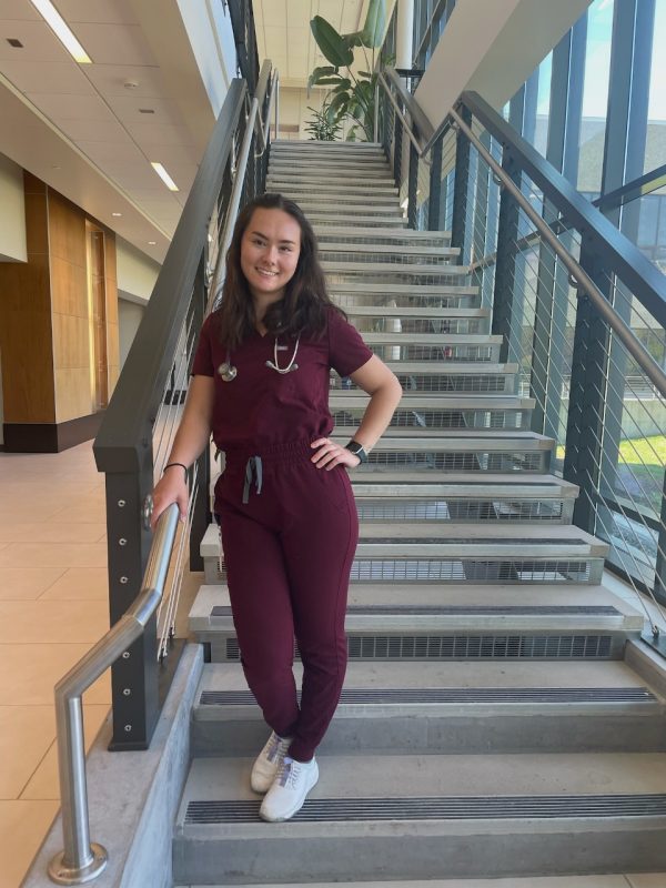 Andrea Conner posing in scrubs in the lobby of the Veterinary Teaching Hospital