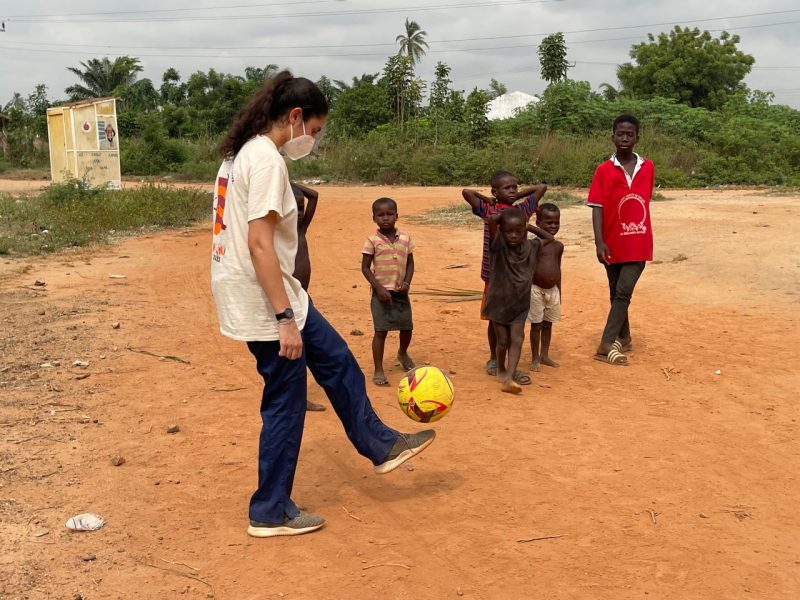 Neena O'Mara kicks a soccer ball with children