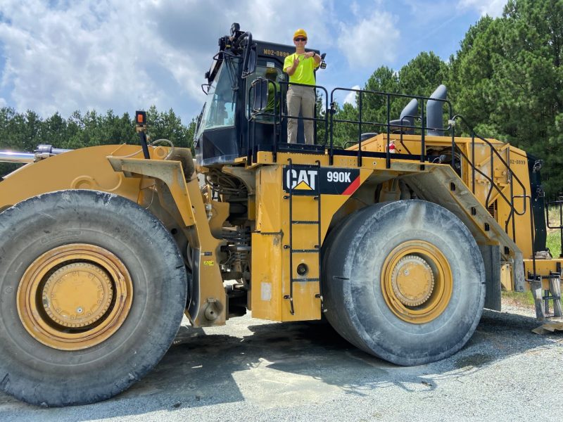 Student stands on top of heavy machinery.