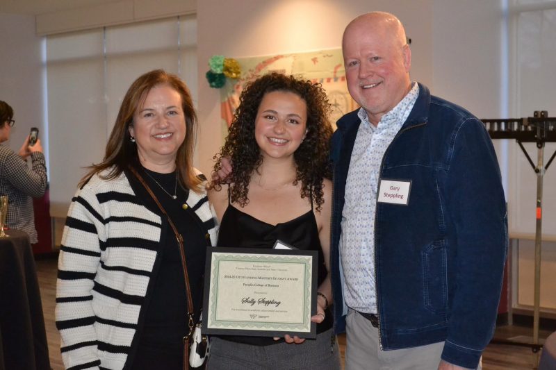 Sally Steppling stands in between her two parents and displays the certificate awarded to her