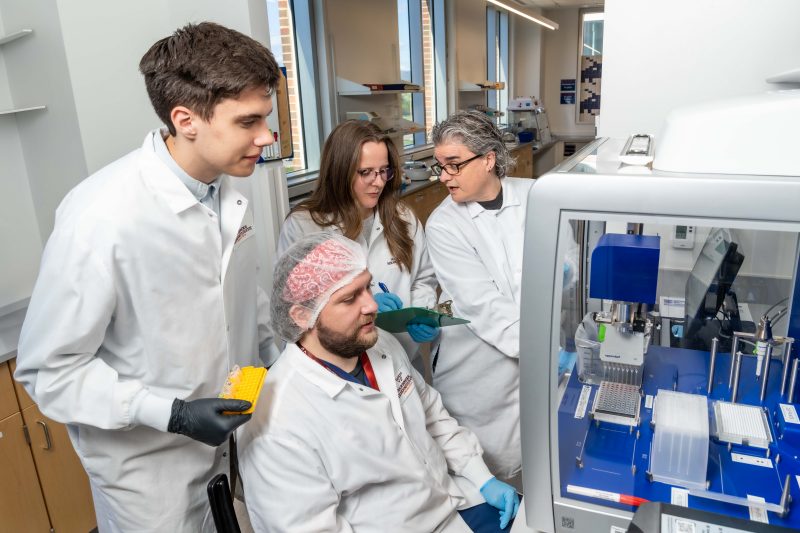 Cancer research Virginia Tech researchers John Janiga, Dzenis Mahmutovic (seated), Katherine Brown, and lead investigator Carla Finkielstein work together in the Molecular Diagnostics Laboratory