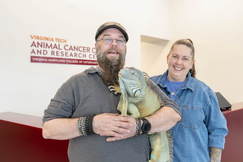 Echo the Iguana Tom and Melissa Smith (at center) with their pet iguana Echo (at center) posing in the lobby of the Animal Cancer Care and Research Center