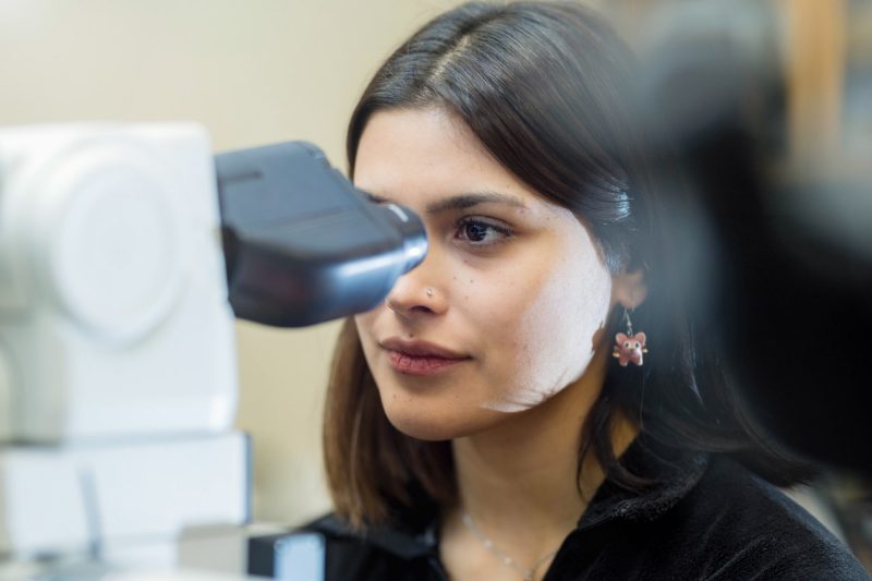 Stefanie Guevara Stefanie Guevara looking through a microscope