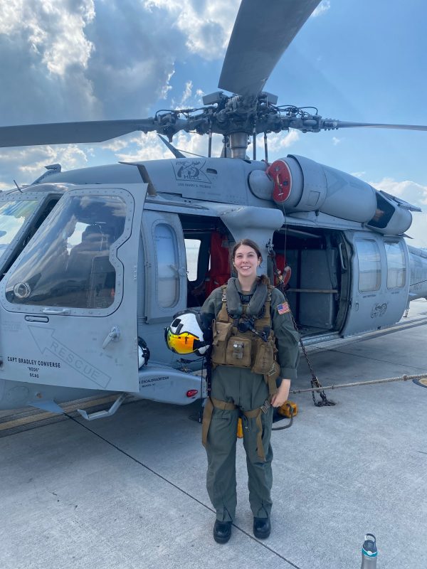 a young woman stands in front of a helicopter