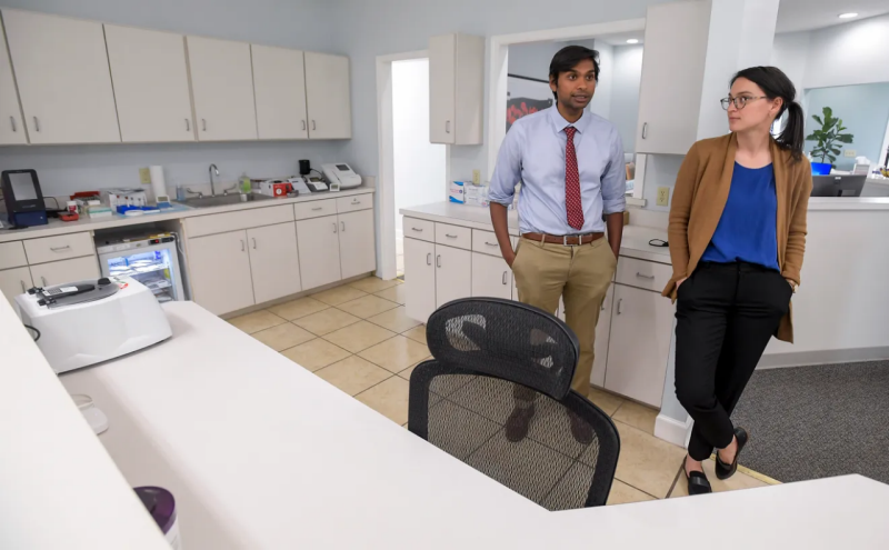 A man and woman stand beside each other in administrative part of doctor's office.