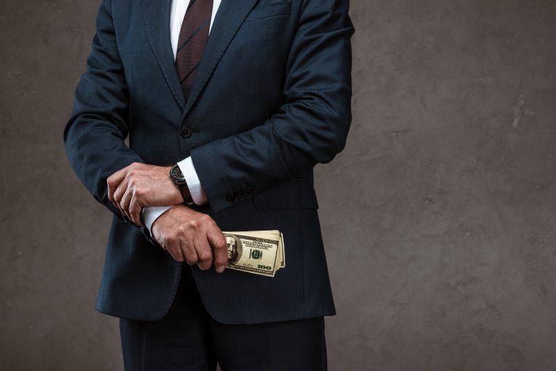 cropped view of businessman holding dollar banknotes in hand on grey