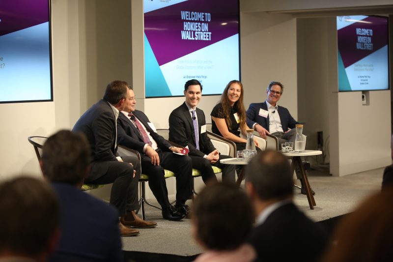 Five people speak in a panel discussion in front of a crowd.