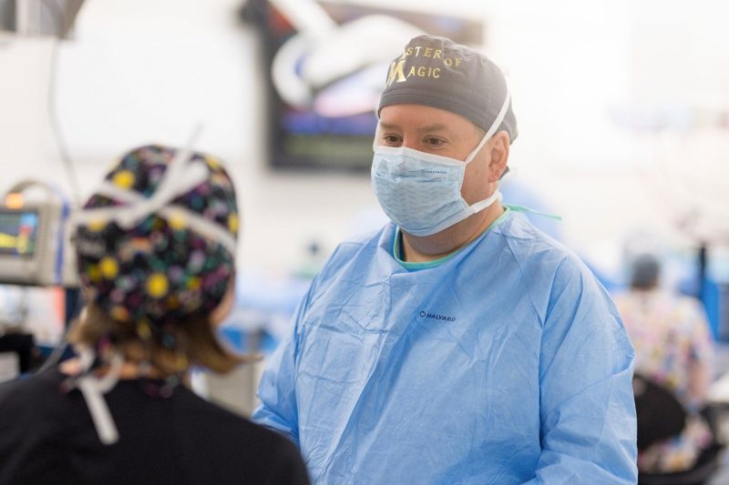 Faculty Awards Michael Nappier in a surgical suite at the Veterinary Teaching Hospital speaking with a vet tech wearing a scrub cap, mask, and surgical gown