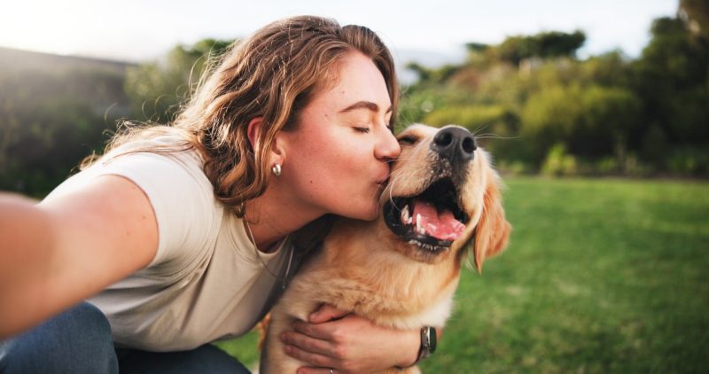 Wellness Tips A woman kissing her dog, showing the animal-human bond that many share.