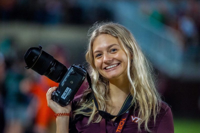 Emma Luis smiles while holding a camera.