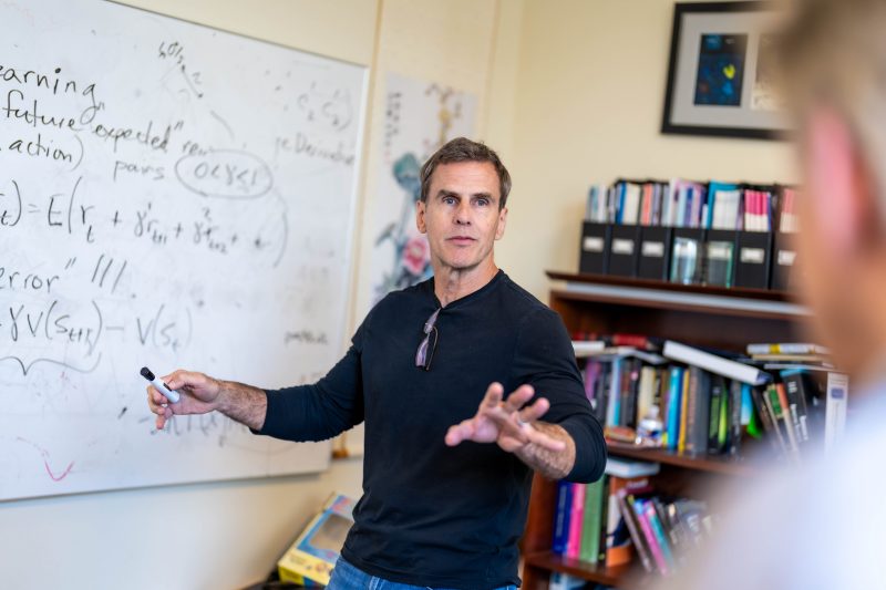 Researcher at white board writing equations.