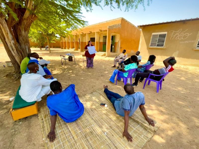 Visiting educator speaks with a group of Senegalese farmers