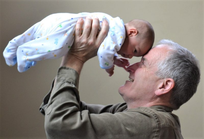 Photo of a grandfather raising a baby in the air,