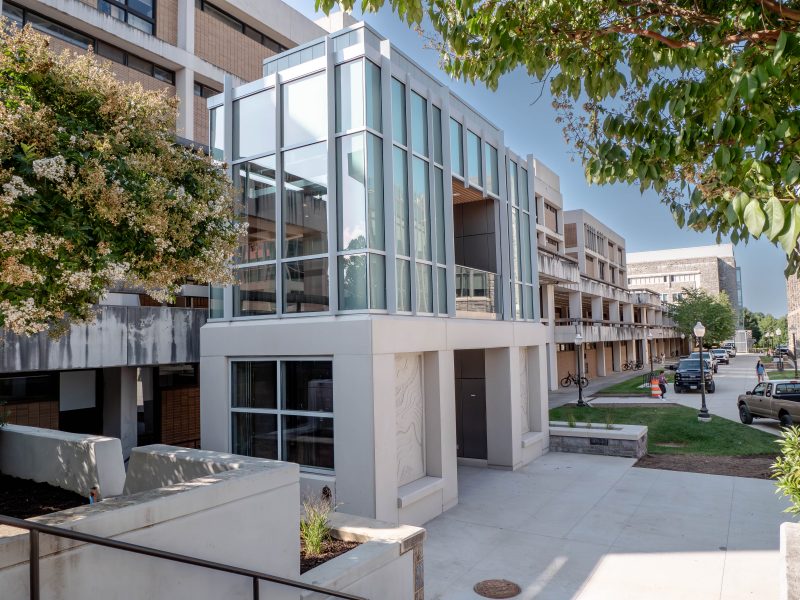 An elevator tower outside of Derring Hall with a concrete base and large glass windows