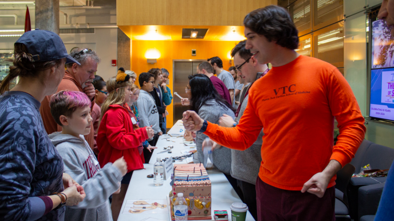 A student with the Virginia Tech Carilion School of Medicine fist bumps a student attending Kids' Tech University.