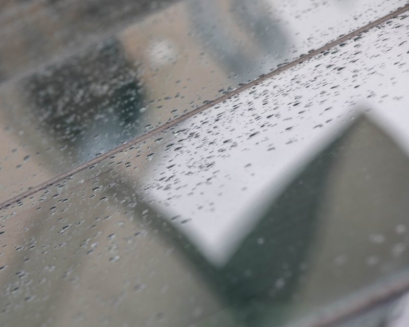 Rainwater collects on a glass surface