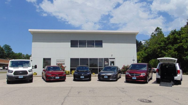 Fleet Services building exterior with sedans, vans, and buses parked out front.